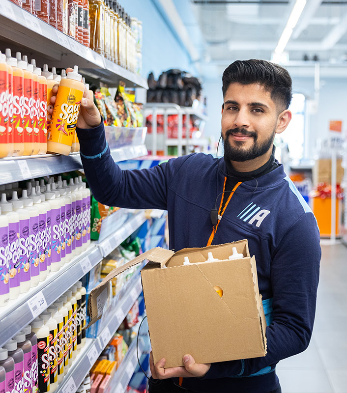 Man in a store holding a product box and bottle