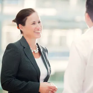 A woman in a suit talking to a man in a white shirt